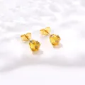Gros plan détaillé de boucles d'oreilles couronne dorées avec zircone jaune à six griffes - Jaune d'Or