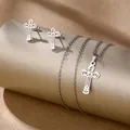 Detailed view of silver hollow cross necklace and stud earrings set on a pedestal - Wave Cross (TZ-484)