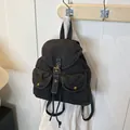 Vintage black denim backpack with flap pockets and bronze buckles on a wooden hook - Black