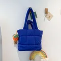 Navy blue quilted puffer tote bag with wide straps and orange plush charm detail - Blue
