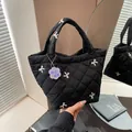 Schwarze gesteppte Handtasche mit weißen Schleifenstickereien und Taschenanhänger - Schwarz