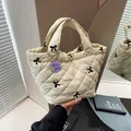 Gesteppte Beuteltasche in Creme mit schwarzer Schleifenstickerei und Blumenanhänger - Gebrochenes Weiß