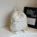 Cream white quilted backpack with black bow pattern and adjustable webbing straps - Off White