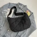Black quilted crescent crossbody bag with adjustable strap and floral charm detail - With Pendant / Black