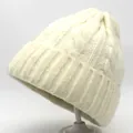 Detailed view of cream cable knit texture and ribbed cuff on a thick winter beanie - Off White