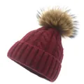 Detail of burgundy knit beanie featuring chunky cable patterns and a large faux fur pom-pom - Burgundy