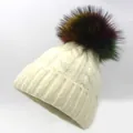 Close-up of beige knit beanie featuring thick cable texture and a colorful faux fur pom-pom - Off White