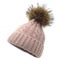 Close-up of pink knitted hat featuring thick cable textures and a brown faux fur pom-pom - Pink