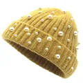 Détail d'un bonnet en maille jaune moutarde orné d'élégantes perles blanches de luxe - Perle Totale Jaune