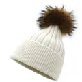 Close-up of ribbed knit winter hat featuring a fluffy raccoon fur pompom in cream white - M (56-58cm) / White