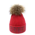 Detailed view of red knit beanie featuring silver star patterns and a fluffy faux fur pompom - M (56-58cm) / Red