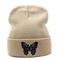 Gros plan sur un bonnet en maille beige avec une broderie papillon noire détaillée - M / Kaki