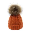 Detalle del tejido de trenzas de un gorro de invierno naranja con gran pompón de piel - Naranja