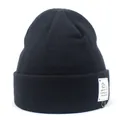 Detail van de zwarte geribbelde muts met witte patch en metalen ring als accessoire - M (56-58cm) / Zwart