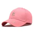 Gorra de béisbol rosa con detalle de letra R bordada vista en un ángulo de 45 grados - M(56-58cm) / Rosa