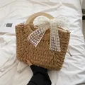 Große Strohtasche mit runden Holzgriffen und einer weißen Spitzen-Schleife dekoriert - Khaki