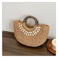 Detail einer Strandtasche aus Stroh mit dekorativen Muscheln und gewebten Rundgriffen - Khaki