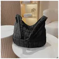 Borsa tote trapuntata nera in morbido tessuto imbottito su un tavolo di marmo elegante - Nero