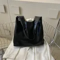 Minimalist black leather tote bag with a soft matte finish and AIBE woven brand label - Black