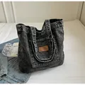 Nahaufnahme der gewaschenen Denim-Tragetasche mit Leder-Logo und robusten Griffen - Schwarz