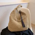 Sac bandoulière en paille beige avec pompon marron foncé sur une chaise moderne - Beige