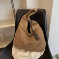 Grand sac hobo en paille tressée marron avec pompon en cuir sur un fauteuil - Kaki