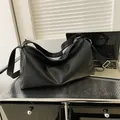 Minimalist black tote bag with cracked stone texture and wide shoulder strap in home office - Black