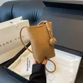 Mini bruine leren crossbodytas met knoopdetail getoond in een luxe geschenkdoos - Khaki