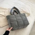 Sac cabas gris matelassé avec poignées rembourrées et étiquette mode sur le lit - Gris