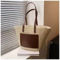 Detail of beige straw tote bag with brown leather pocket and handles on white book - Off White