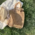 Handgefertigte khakifarbene Stroh-Tote-Bag mit hohler Strickstruktur auf einer Picknickwiese - Khaki