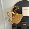 Beige woven handbag with brown leather flap, pearl clasp, and white lace bow detail - Khaki