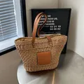 Minimalistische beige gewebte Strohtasche mit braunen Ledergriffen und quadratischem Patch - Khaki