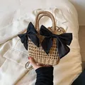 Light brown woven straw bucket bag featuring two large black bows and a slim shoulder strap - Dual Black Bow Style / Khaki