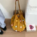 Close-up of a yellow hollow crochet bag with 3D floral accents and leather handles - Yellow