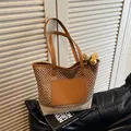 Dettaglio della borsa tote in paglia intrecciata con inserti in pelle marrone su divano - Marrone