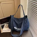 Donkerblauwe denim crossbodytas met witte REPLACE-opdruk in een stijlvolle setting - Donkerblauw