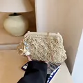 Beigefarbene gewebte Stroh-Cloud-Tasche mit Goldkette und Anhängern für den Urlaub - Gebrochenes Weiß