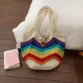 Detail of colorful rainbow stripe knit bag with brown leather clasp and woven texture - White
