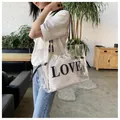 Detail der transparenten PVC-Tasche mit weißem Kordelzugbeutel und LOVE-Schriftzug - Klarweiß