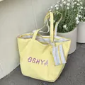 Große gelbe Tragetasche mit GSHYA-Logo und gestreiftem Münztaschen-Anhänger - Gansgelb