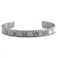 Detailed macro view of silver Roman numeral cuff bracelet with white enamel and serrated edges - White Roman Numeral