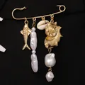 Detalle de broche temático oceánico con pez dorado, conchas y perlas barrocas blancas. - Dorado (11091)