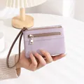 Close-up of purple litchi grain texture wallet with double gold zippers and wrist strap - Purple