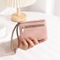Detail showing pink pebble leather texture on a compact double zipper wristlet wallet - Pink