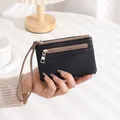 Handheld black pebble leather wallet featuring dual gold zippers and a wristlet strap - Black