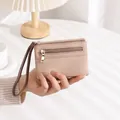 Detail of beige lychee leather wallet with double zippers and brown wristlet strap - Apricot