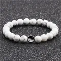 Dettaglio di perline in turchese bianco con trama marmorea e perla con simbolo yin yang - Howlite