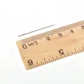 Ago da cucito in acciaio da 4cm con cruna grande posizionato su un righello di legno - 0.6x32mm