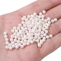 White faux glass pearls in hand showing high luster finish for DIY jewelry making - 2 Pieces/Pack / Approx. 4mm (1mm Hole) / White